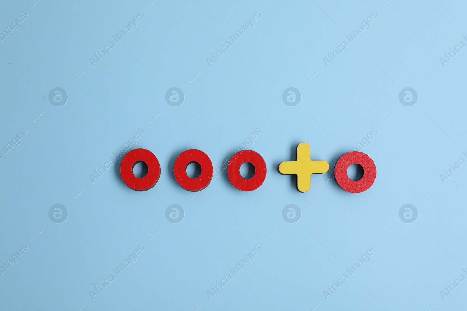 Photo of Choice concept. Red wooden circles and yellow cross on light blue background, flat lay