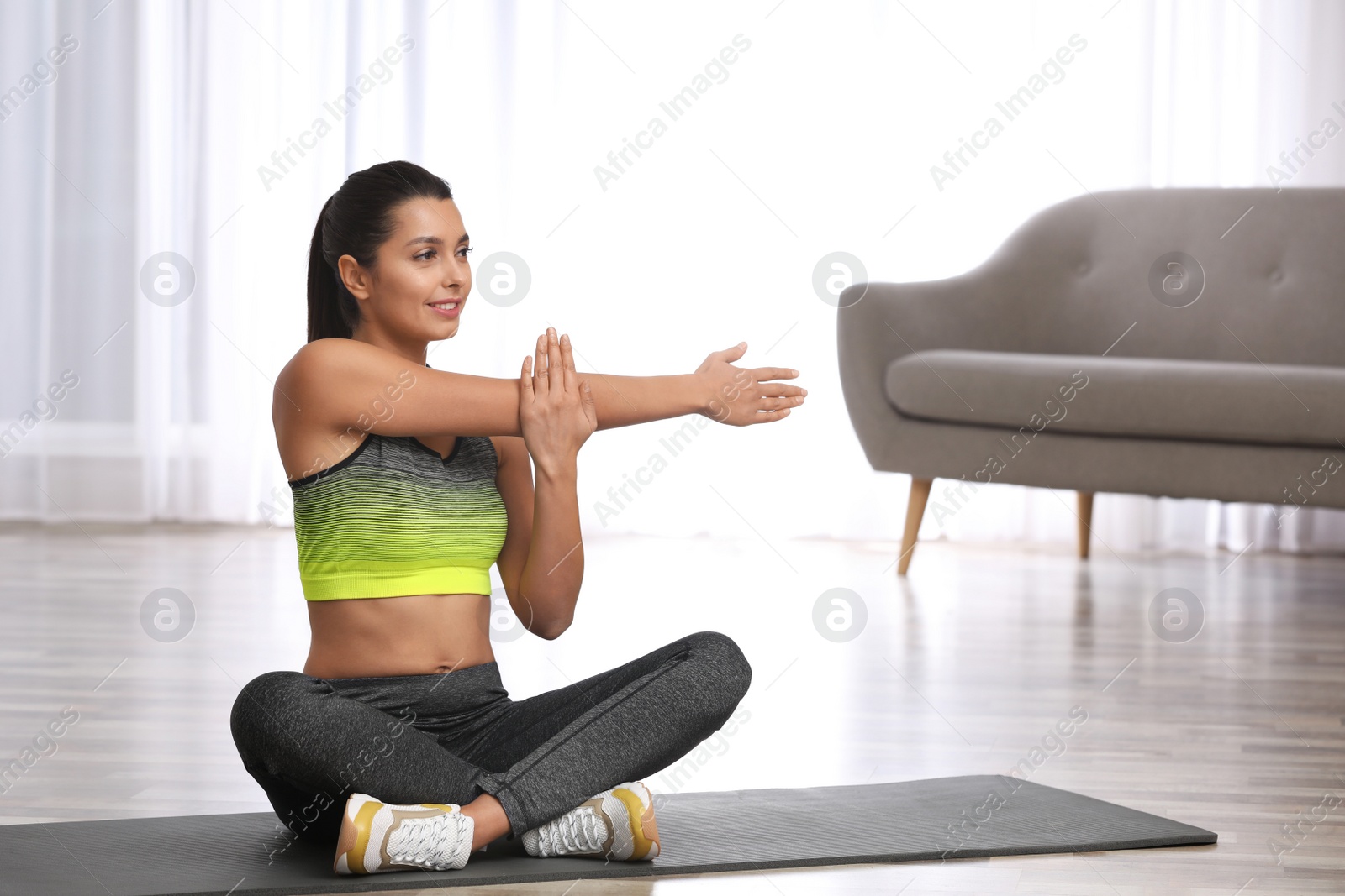 Photo of Young woman in fitness clothes doing exercise at home