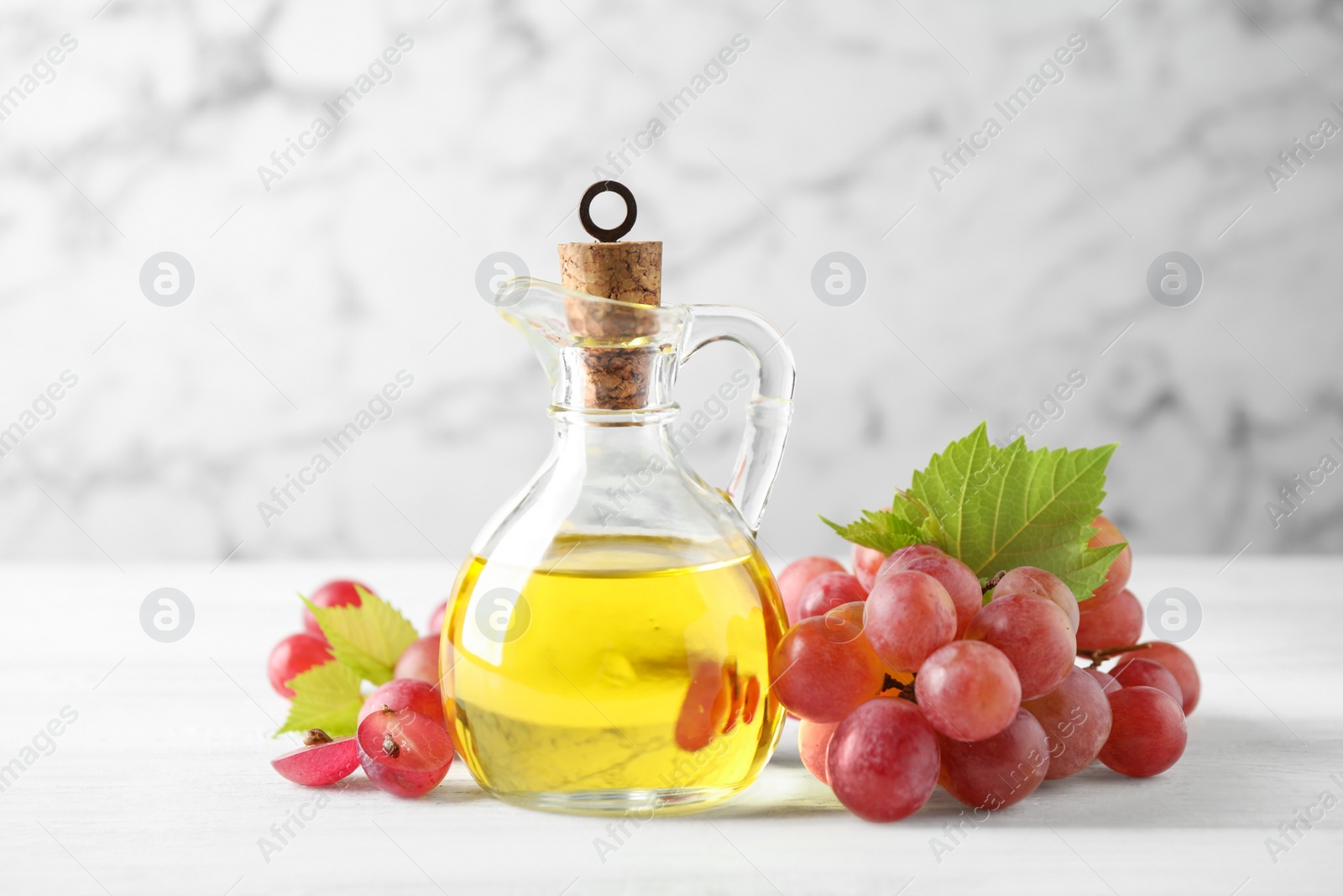 Photo of Natural grape seed oil and fresh berries on white wooden table. Organic cosmetic