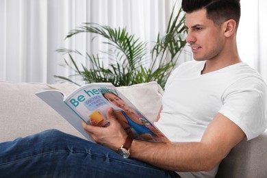 Photo of Man reading magazine on sofa in living room