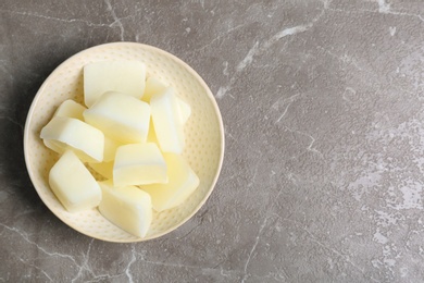 Photo of Bowl with milk ice cubes on grey background, top view. Space for text