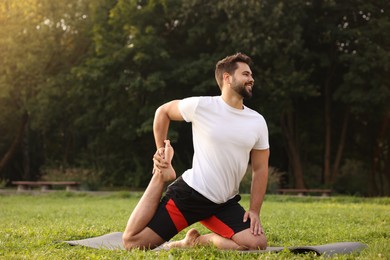 Photo of Man practicing yoga on mat in park