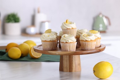 Photo of Delicious lemon cupcakes with white cream and lemons on table indoors