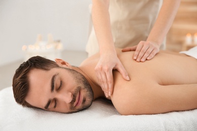 Handsome man receiving back massage in spa salon