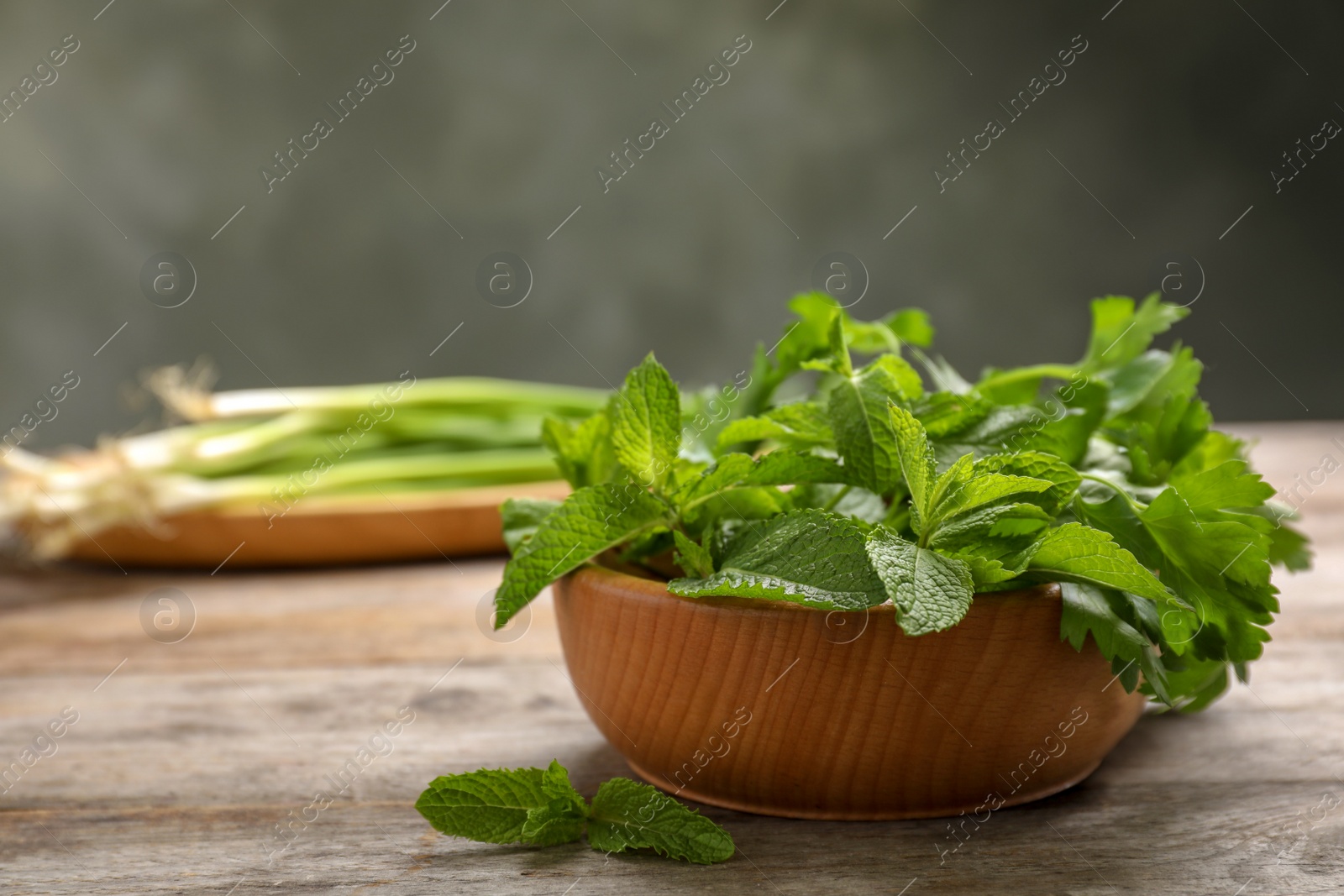 Photo of Bowl with fresh herbs on wooden table