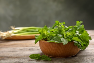 Photo of Bowl with fresh herbs on wooden table