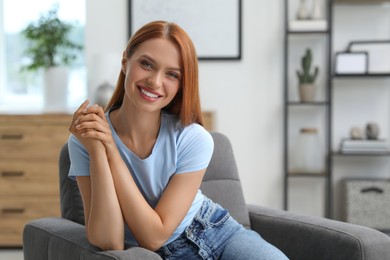 Photo of Portrait of beautiful young woman with red hair at home. Attractive lady smiling and looking into camera. Space for text