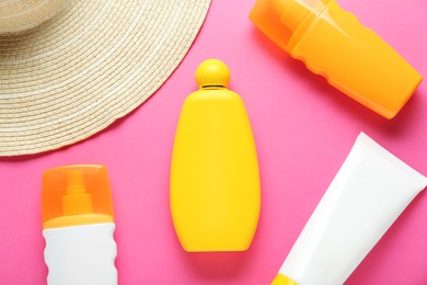 Different suntan products and straw hat on pink background, flat lay