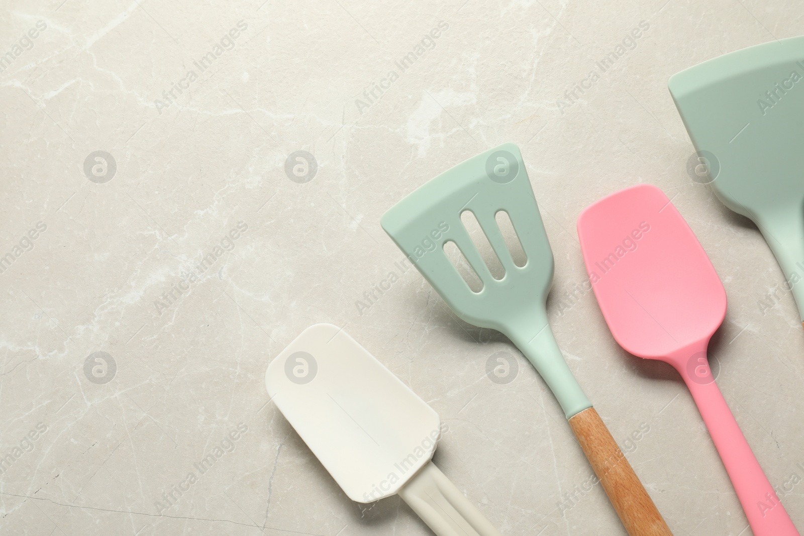 Photo of Different spatulas on light marble table, flat lay. Space for text