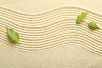 Zen rock garden. Wave pattern and green leaves on beige sand, top view