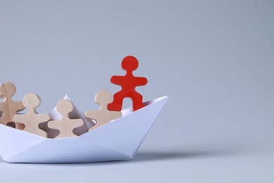 Red figure among wooden ones in paper boat on white background, space for text. Recruiter searching employee
