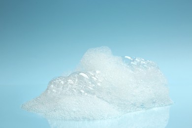 Photo of Drop of fluffy bath foam on turquoise background