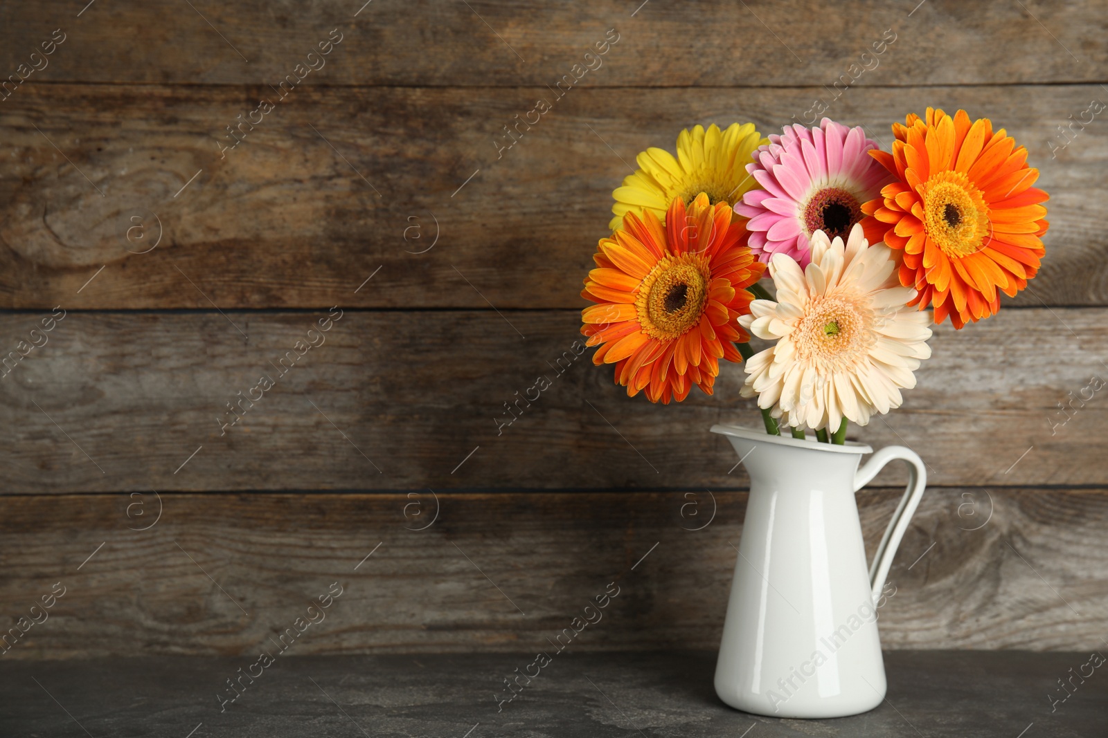 Photo of Bouquet of beautiful bright gerbera flowers in vase on table against wooden background. Space for text
