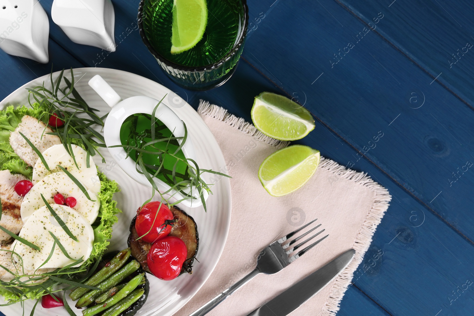 Photo of Delicious mozzarella, chicken, vegetables and drink with tarragon served on blue wooden table, flat lay. Space for text