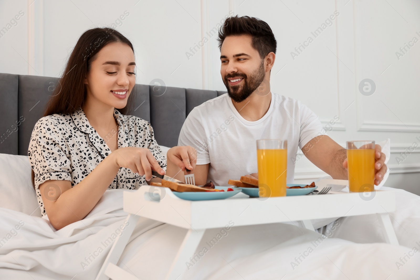 Photo of Happy couple having breakfast on bed at home