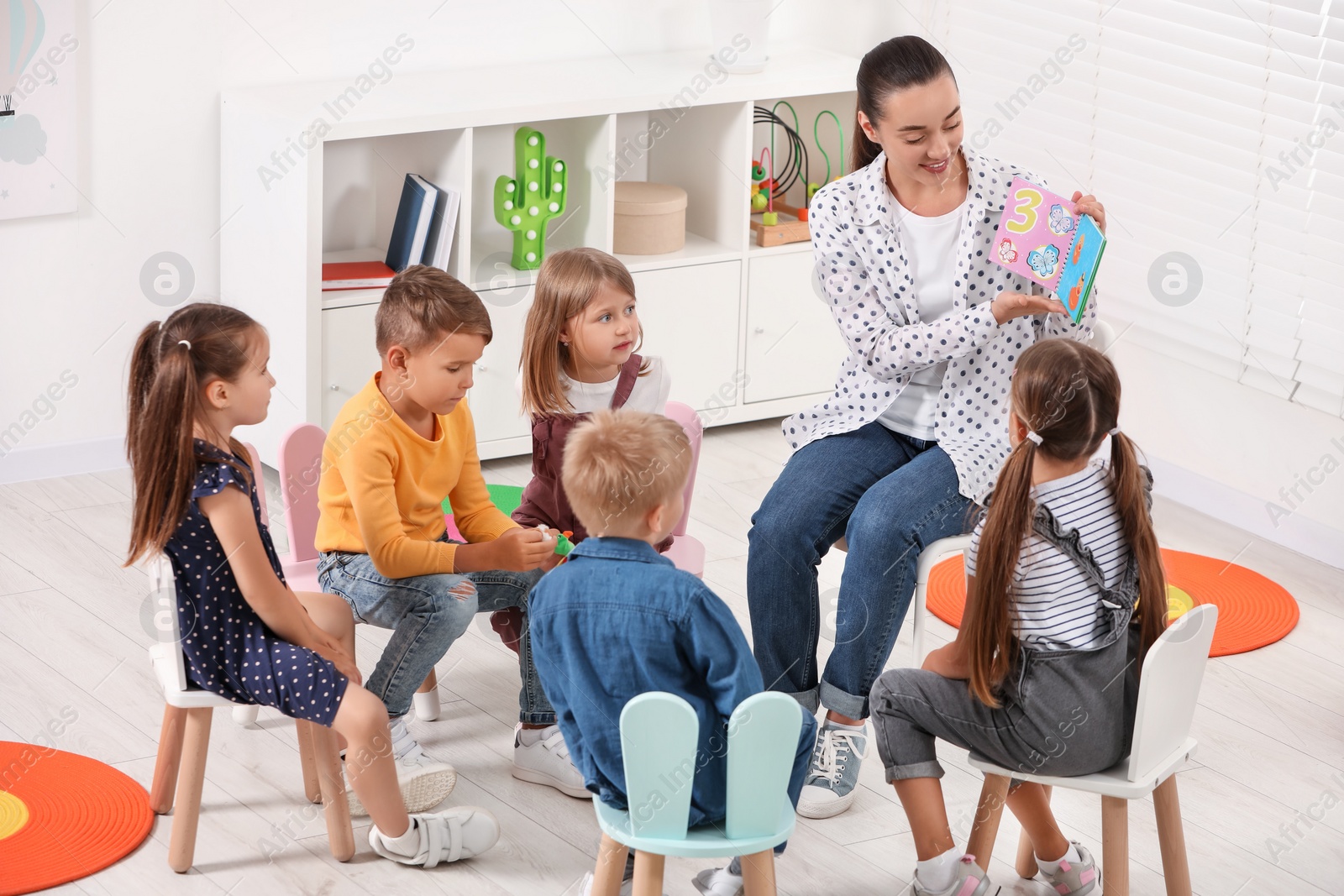 Photo of Nursery teacher and group of cute little children learning numbers in kindergarten. Playtime activities