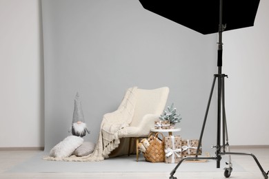 Photo of Stylish photo zone with armchair and Christmas decor in professional studio