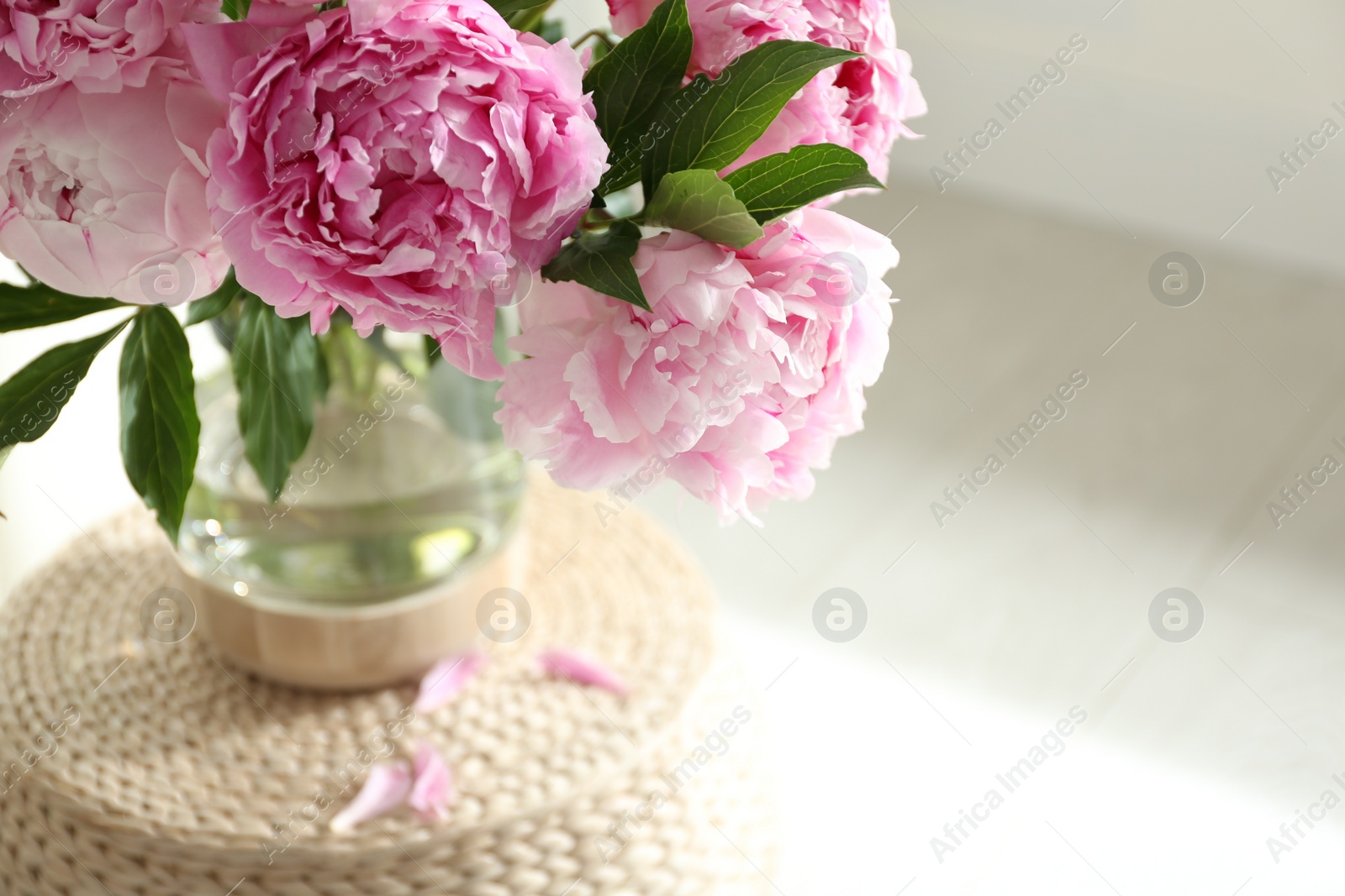 Photo of Bouquet of beautiful peonies on pouf indoors, closeup. Space for text