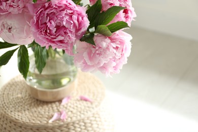 Photo of Bouquet of beautiful peonies on pouf indoors, closeup. Space for text