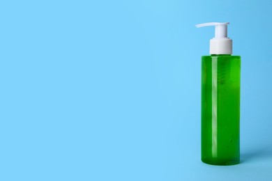 Photo of Bottle of face cleansing product on light blue background. Space for text