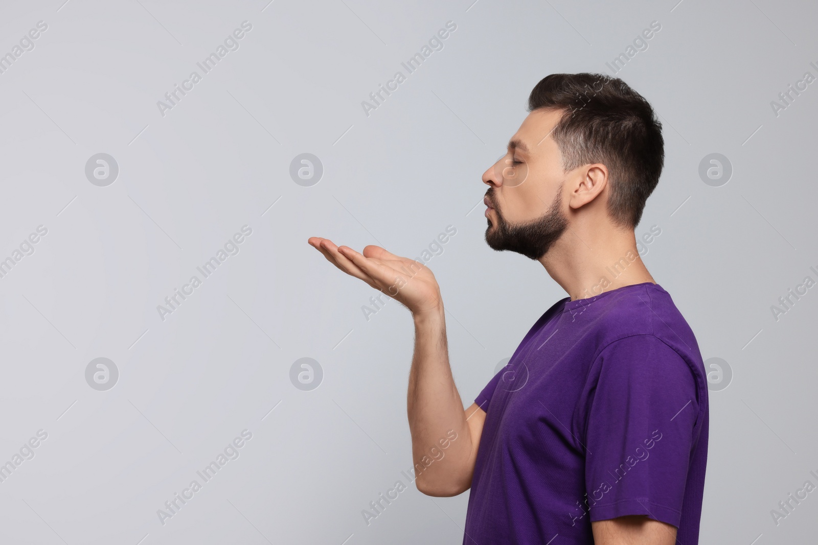 Photo of Handsome man blowing kiss on light grey background. Space for text