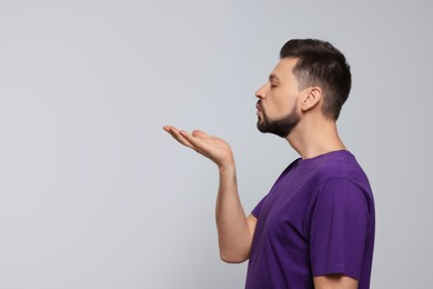 Handsome man blowing kiss on light grey background. Space for text