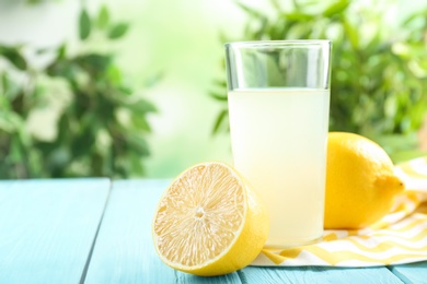 Photo of Freshly squeezed lemon juice in glass on cyan wooden table