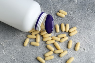 Photo of White medical bottle and pills on light gray table, flat lay