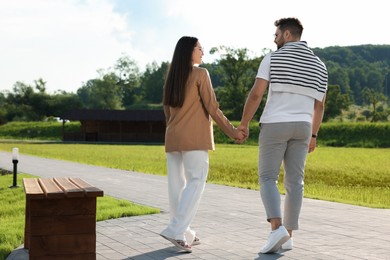 Photo of Romantic date. Beautiful couple walking in park on sunny day, back view