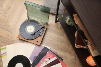 Stylish turntable and vinyl records on floor indoors, above view