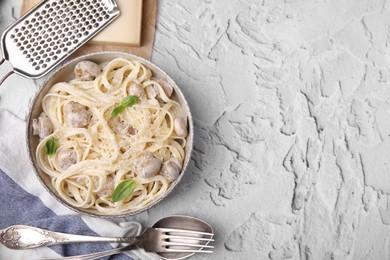 Photo of Delicious pasta with mushrooms and cheese served on light grey textured background, flat lay. Space for text