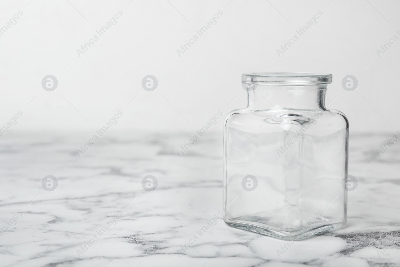 Photo of Empty glass jar on white marble table, space for text