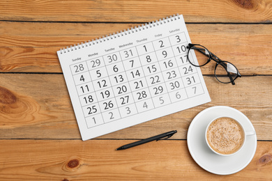 Flat lay composition with calendar and cup of coffee on wooden table