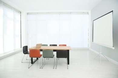 Conference room interior with wooden table and video projection screen