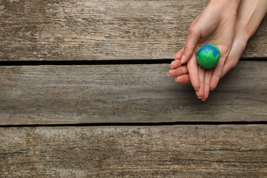 Photo of Happy Earth Day. Woman with plasticine planet at wooden table, top view and space for text