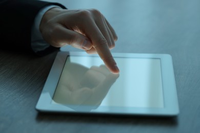 Man using tablet at wooden table, closeup