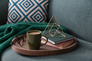Stylish tray with different interior elements and coffee on sofa
