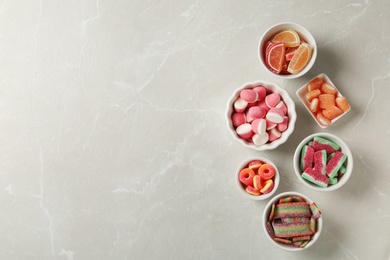 Photo of Flat lay composition with bowls of different jelly candies on light marble background. Space for text