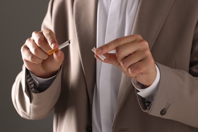 Stop smoking concept. Man holding pieces of broken cigarette on gray background, closeup