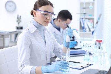 Photo of Scientist dripping sample into beaker in laboratory