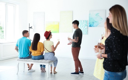 Group of people with glasses of champagne at exhibition in art gallery