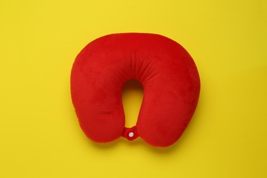 Photo of Red travel pillow on yellow background, top view