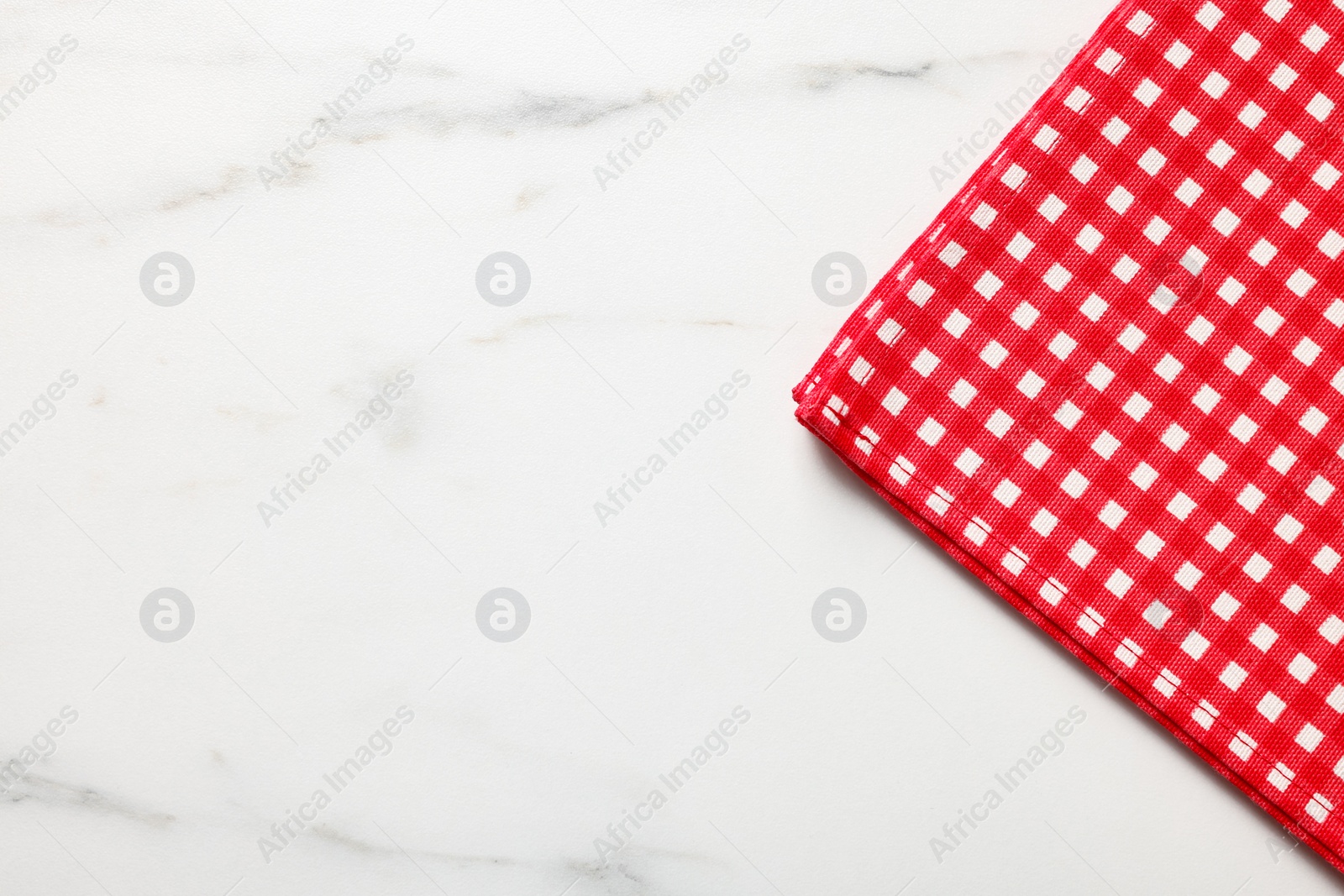 Photo of Red checkered tablecloth on white marble table, top view. Space for text