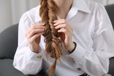 Photo of Woman with braided hair on sofa indoors, closeup