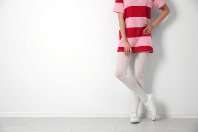 Woman wearing tights near white wall, closeup. Space for text