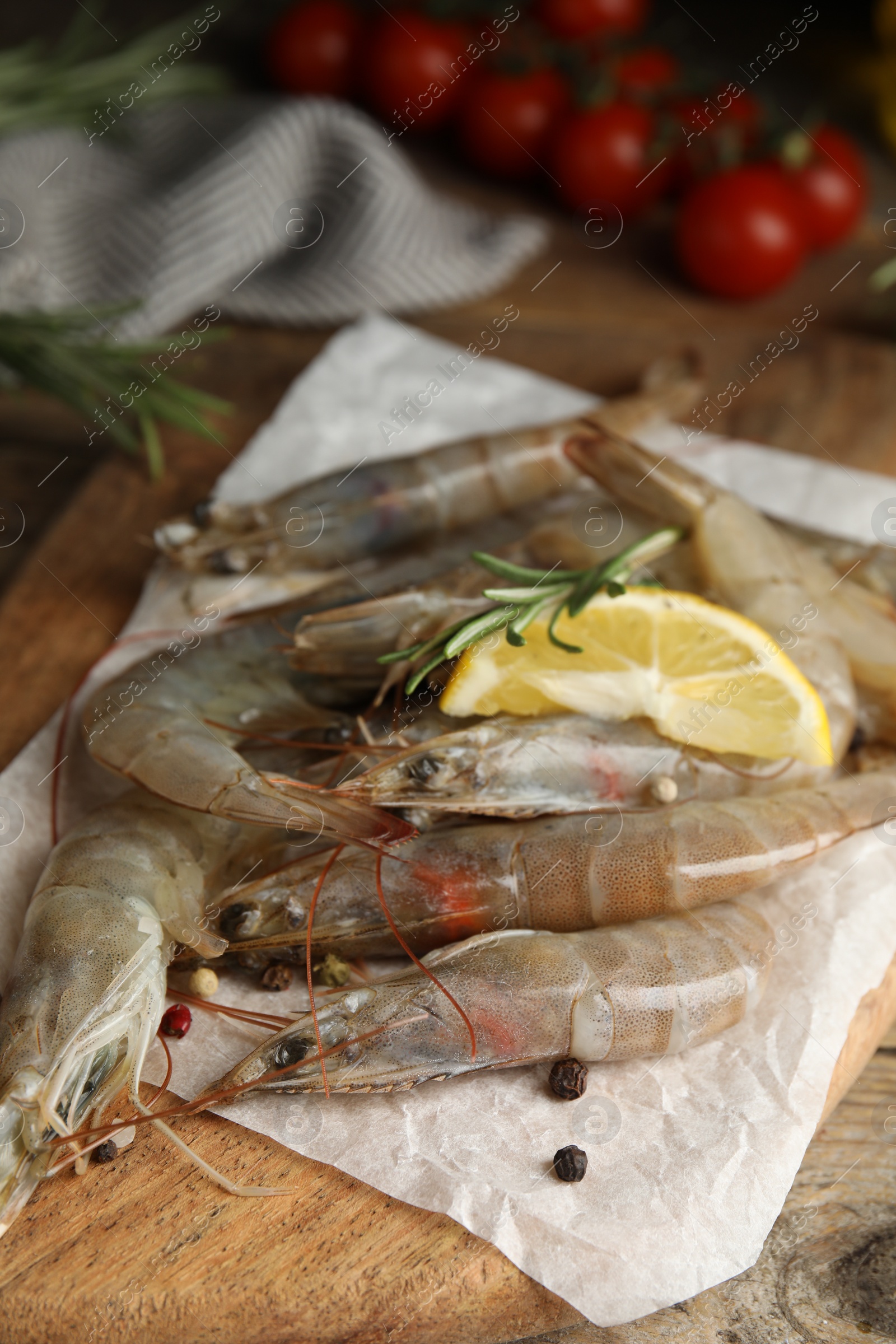 Photo of Fresh raw shrimps with lemon slice and rosemary on wooden table