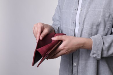 Poor woman with empty wallet on light grey background, closeup. Space for text