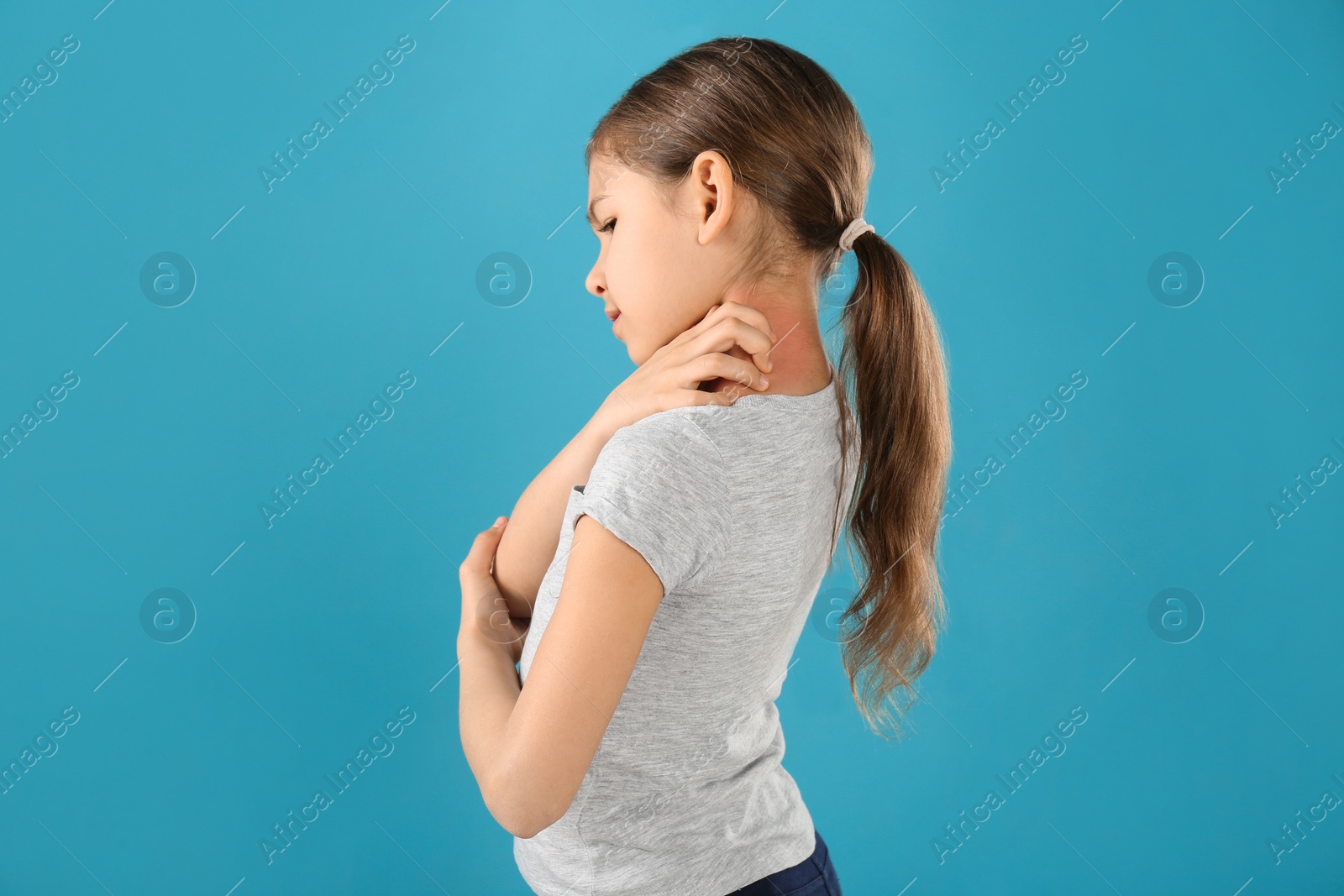 Photo of Little girl scratching neck on color background. Allergy symptoms