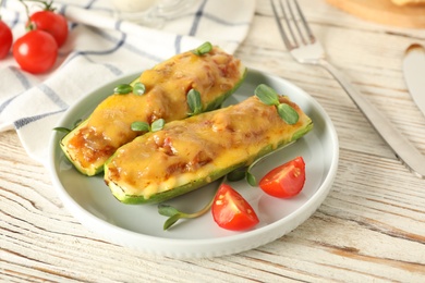 Photo of Baked stuffed zucchinis served on white wooden table, closeup