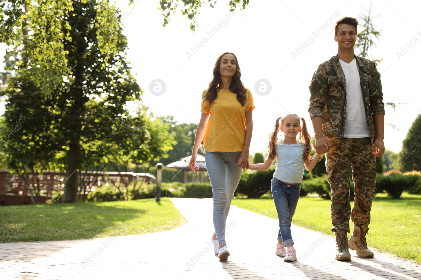 Photo of Man in military uniform and his family walking at sunny park